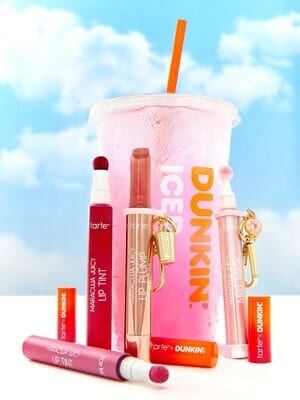 Tarte lip makeup and a pink Dunkin' drink cup against a cloudy blue sky.