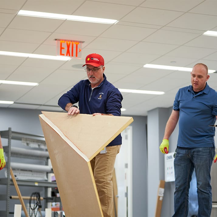 Man holding up a section of tapered insulation as another man looks on.