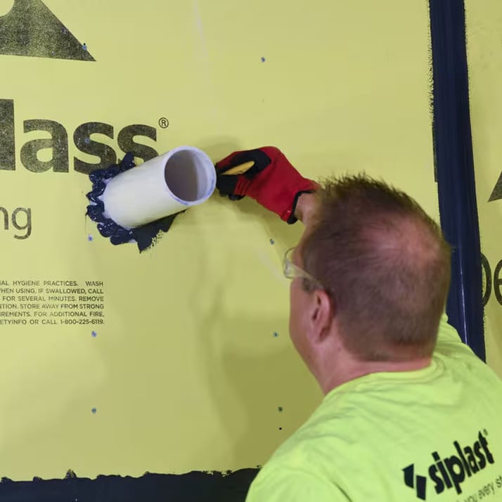 Man in bright yellow tshirt marking measurements on a PVC pipe coming our of an AW barrier.