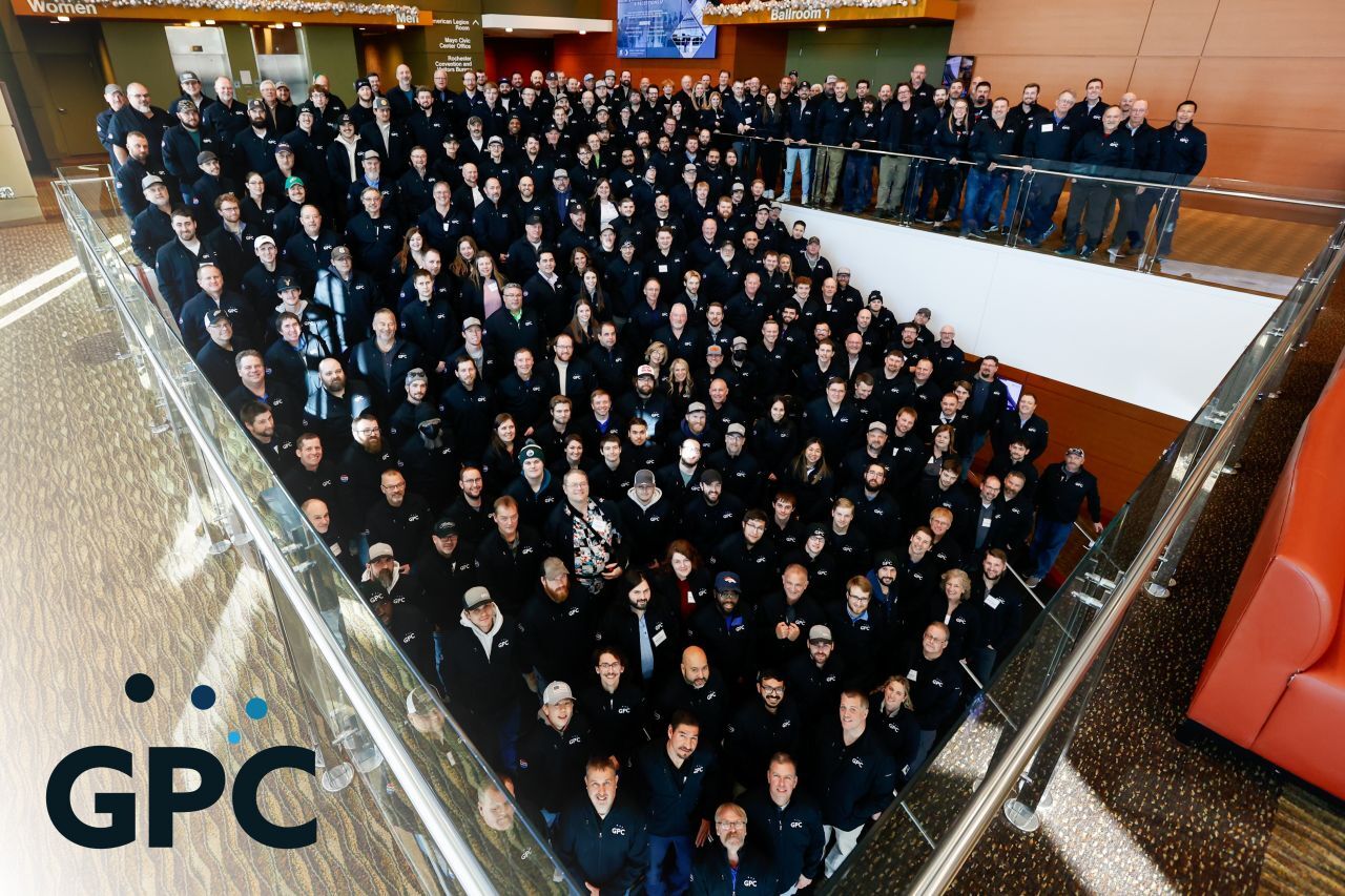 Overhead shot of a large group wearing black GPC jackets on stairs indoors.