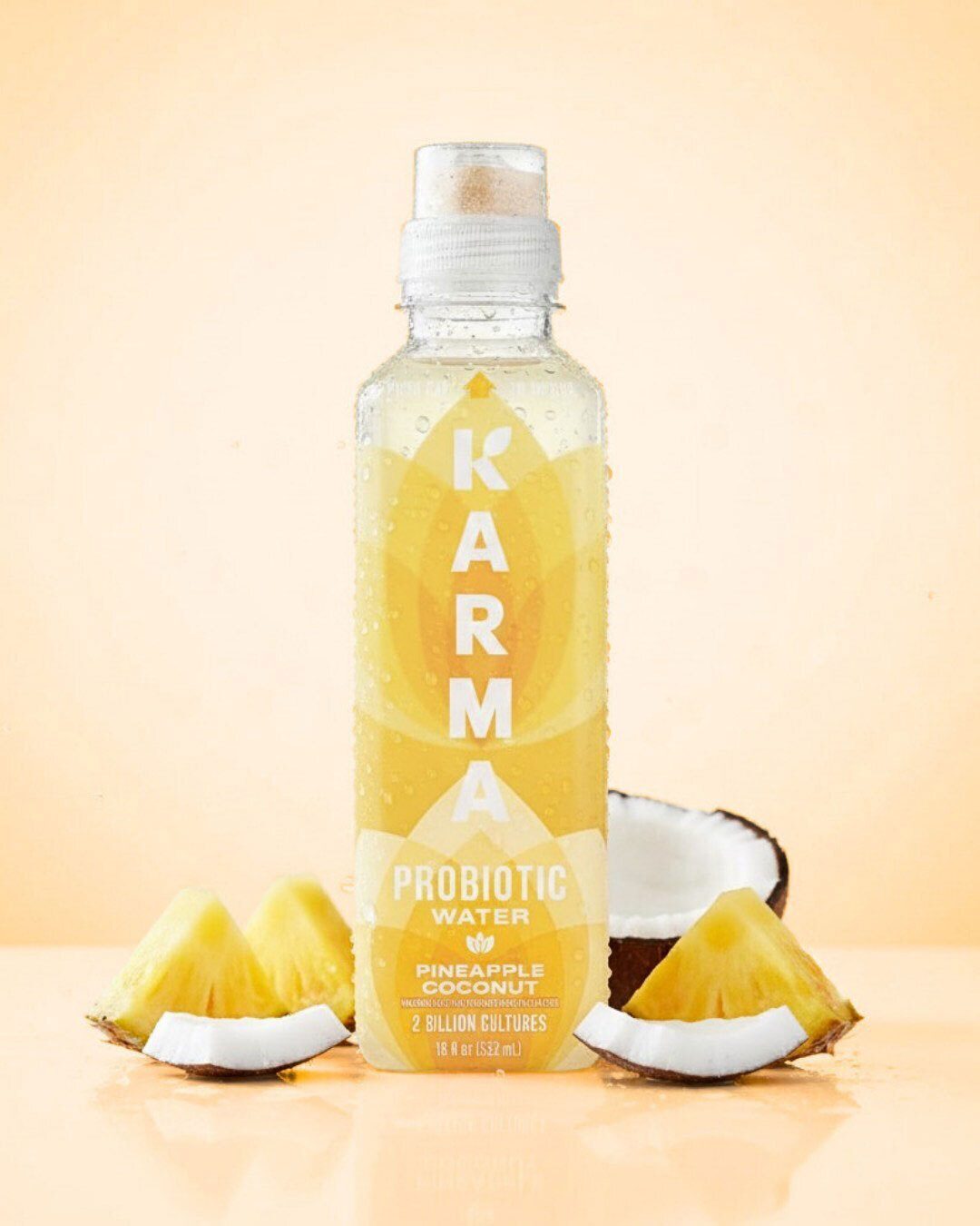 Karma Pineapple Coconut Probiotic Water bottle with fruit slices.