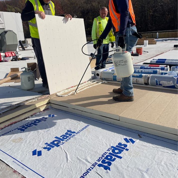 Roofer standing on coverboard and vapor retarder.