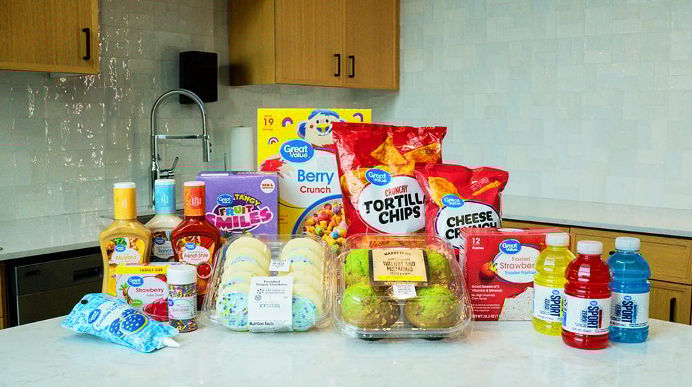 A variety of Great Value brand groceries including snacks, cereals, dressings, and drinks, on a kitchen counter.