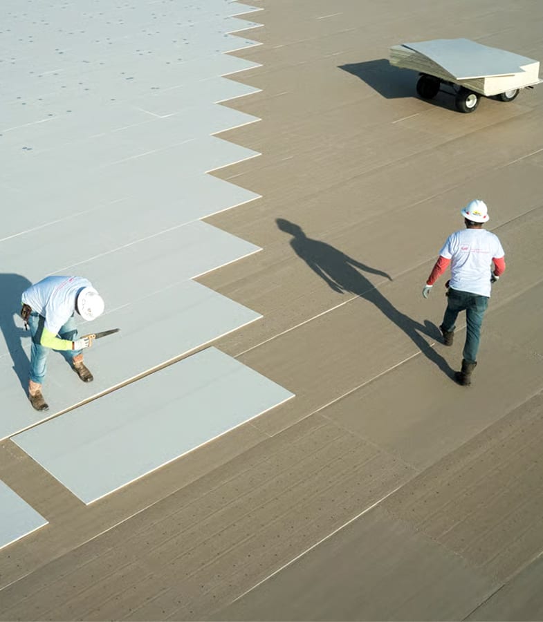 Two roofers next to sections of HD Polyiso insulation in place.