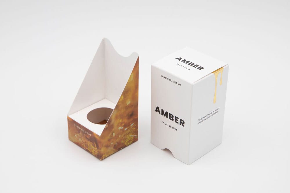 Amber face serum packaging: open amber-patterned interior, closed white exterior with drip graphic.