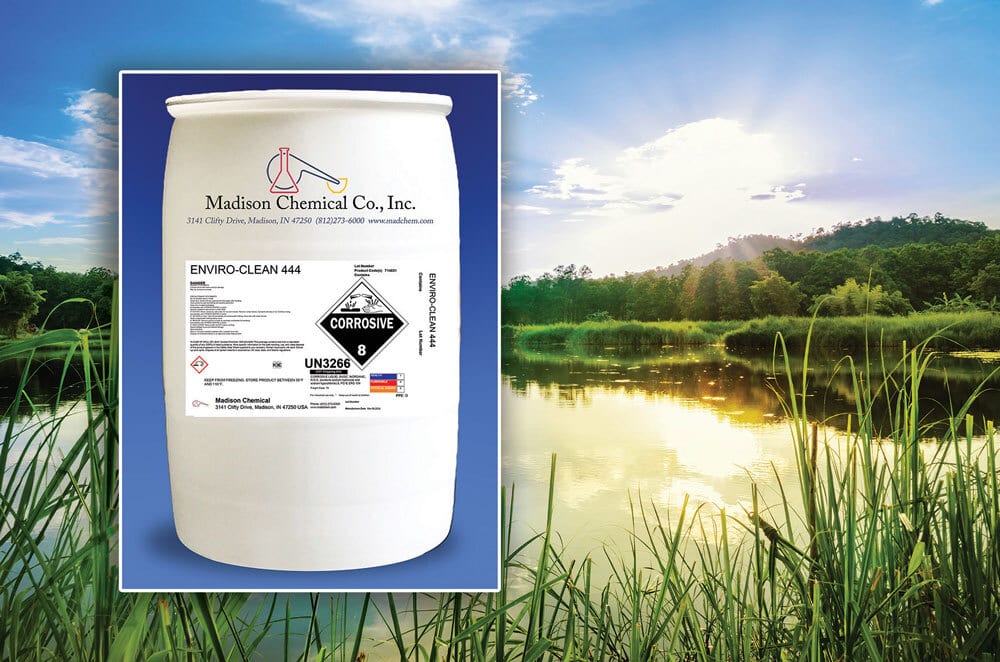 Corrosive chemical drum "ENVIRO-CLEAN 444" on a natural landscape with a lake and forest.