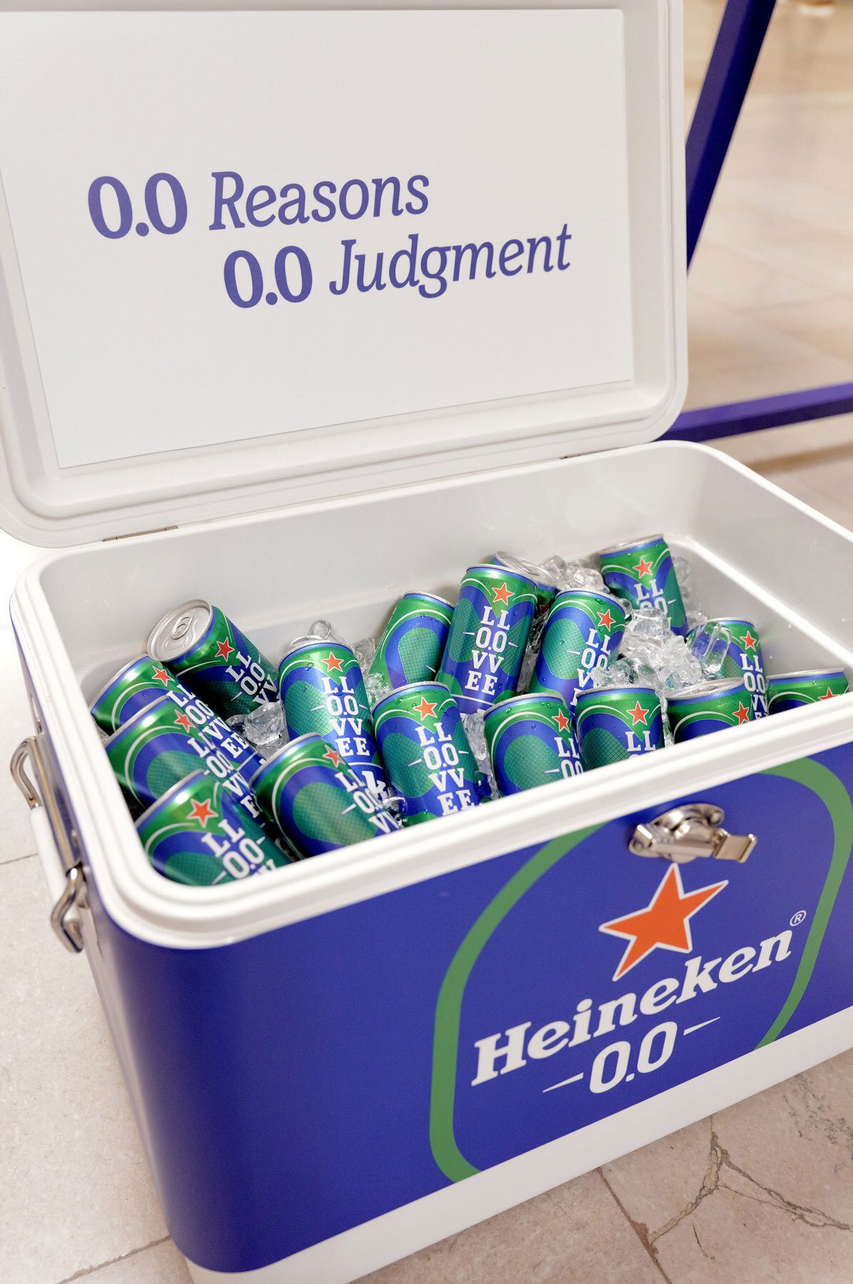 A Heineken 0.0 cooler with "0.0 Reasons 0.0 Judgment" on the lid, filled with cans and ice.