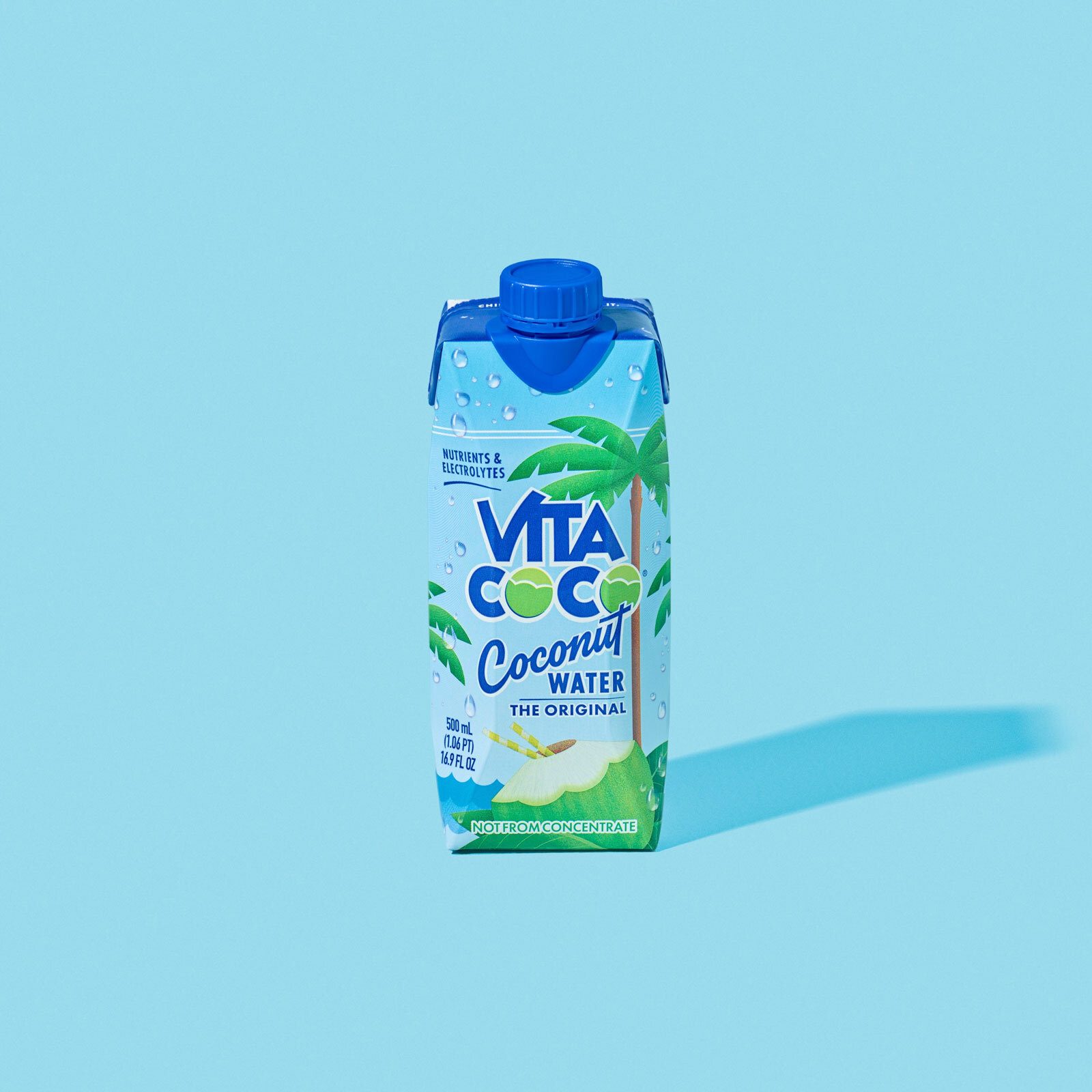 Vita Coco coconut water carton on a light blue background, casting a shadow.