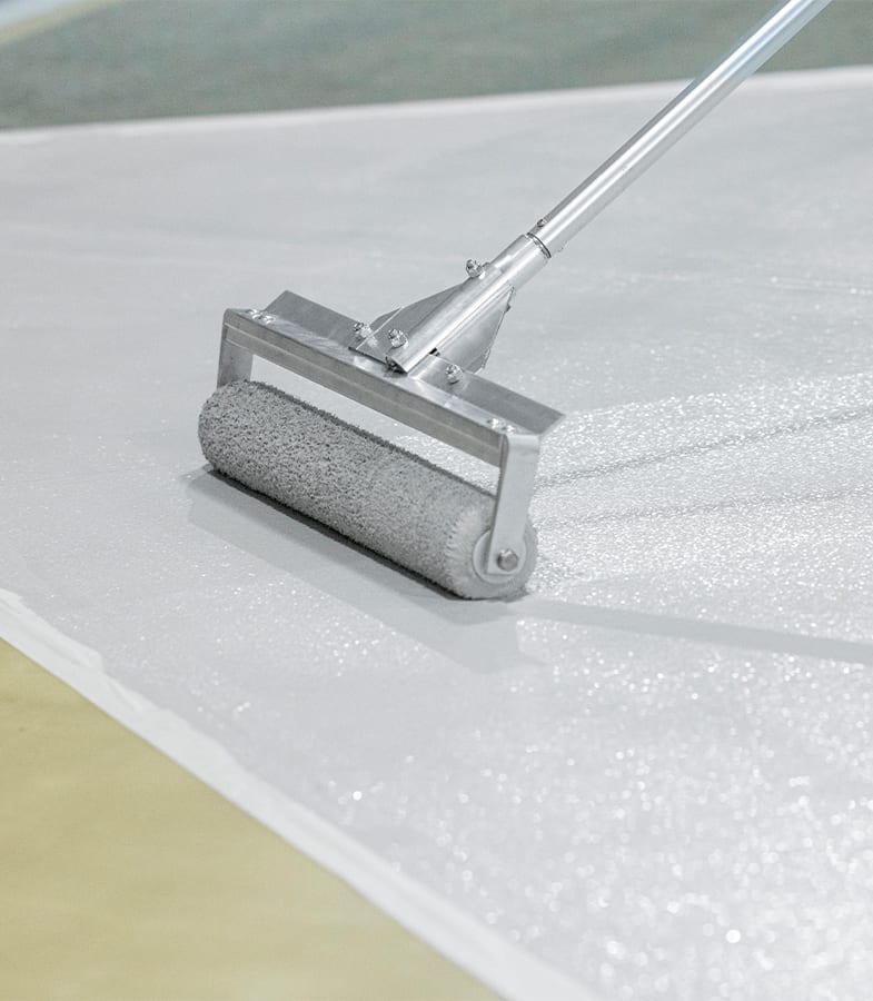 Closeup of a roller applying coating to a traffic walkway.