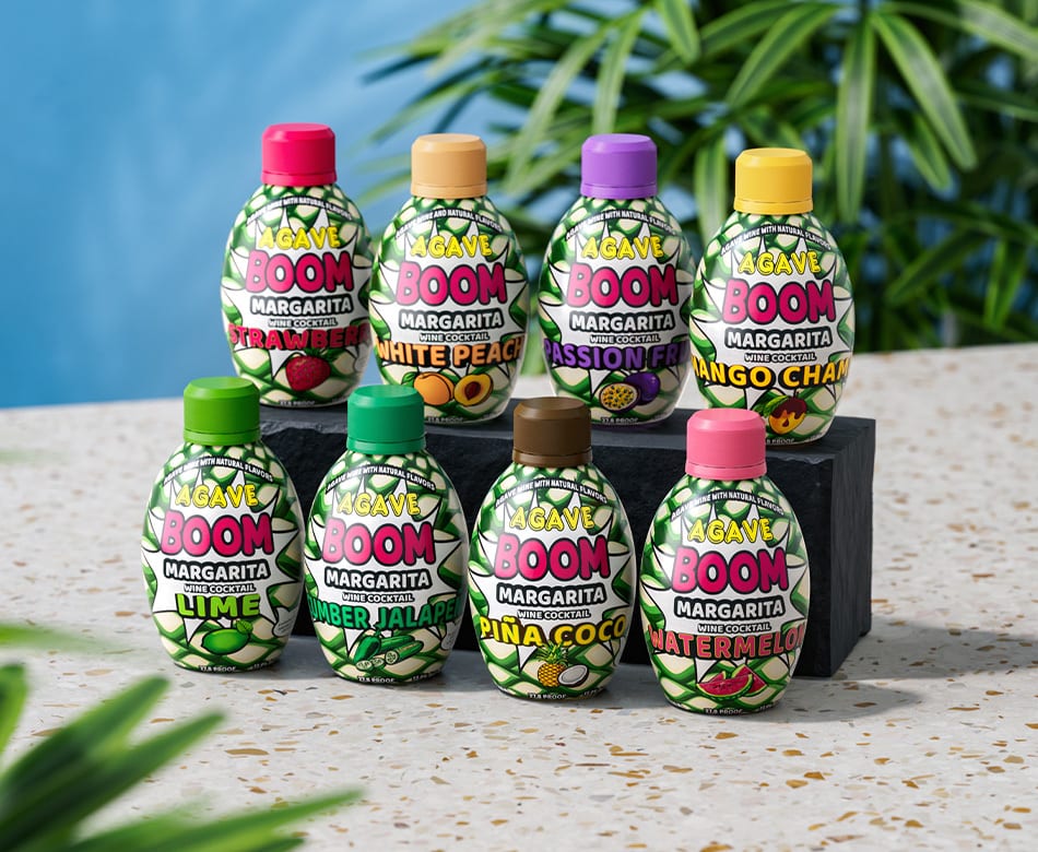 Eight "Agave Boom Margarita" wine cocktail bottles in assorted fruit flavors, displayed on a counter.