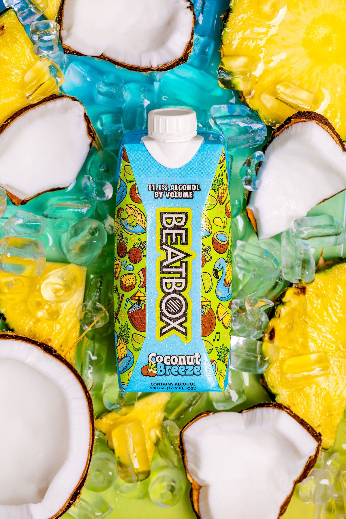 A Beatbox Coconut Breeze carton, surrounded by fresh coconut, pineapple, and ice cubes.