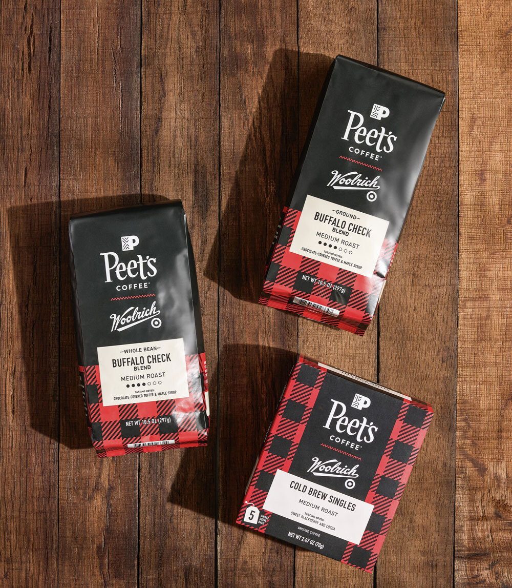 Three Peet's Coffee x Woolrich buffalo check products on a wooden surface.