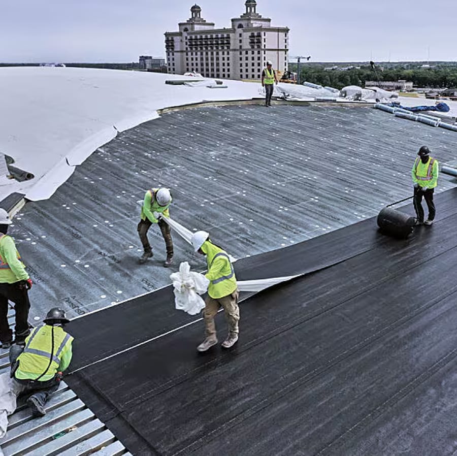 Crew of roofers installing the layers of a commercial roof.