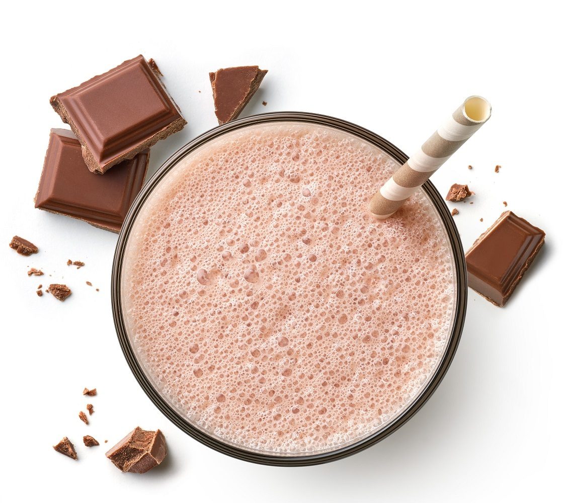 Foamy chocolate milkshake with straw and chocolate pieces, top-down view.