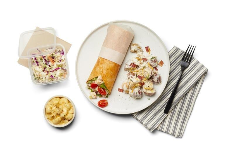 A lunch meal featuring a chicken wrap, creamy potato salad, coleslaw, and macaroni and cheese.