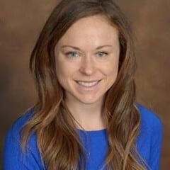 Smiling woman with long brown hair, blue top.