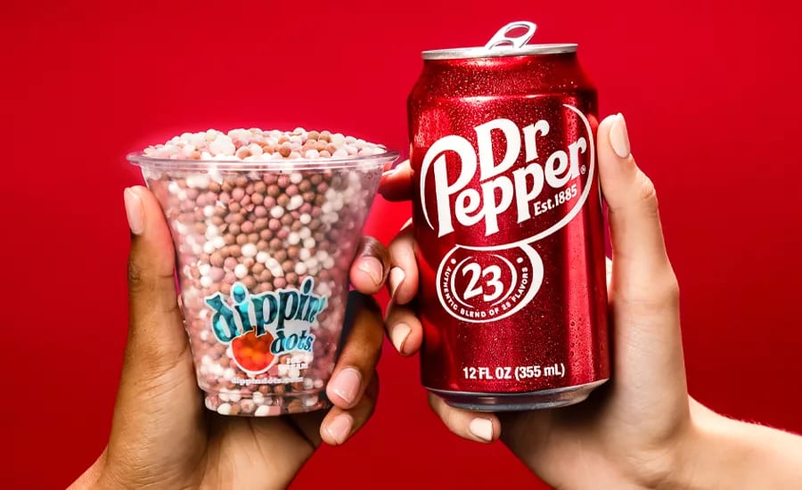 Two hands hold a cup of Dippin' Dots and a Dr. Pepper can on a red background.