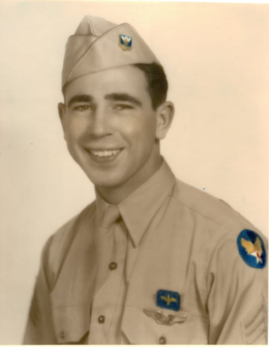 A young man in a WWII-era US Army Air Force uniform, complete with hat and insignia, smiling at the camera.