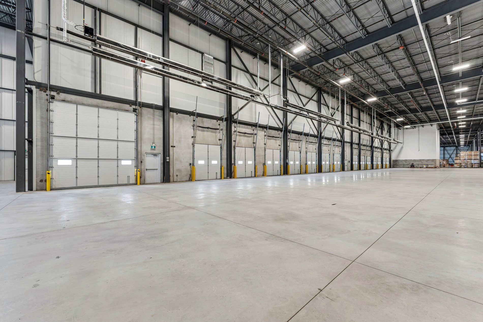 Large, empty industrial warehouse with numerous loading dock doors.