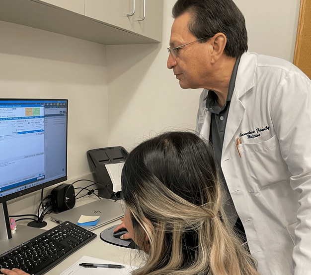 Doctor and staff look at computer in medical office.