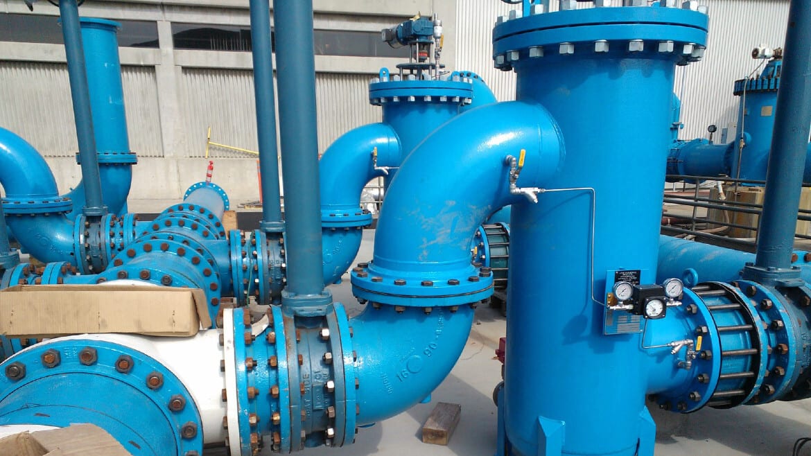 Interconnected large blue industrial pipes, valves, and gauges in a fluid management system.