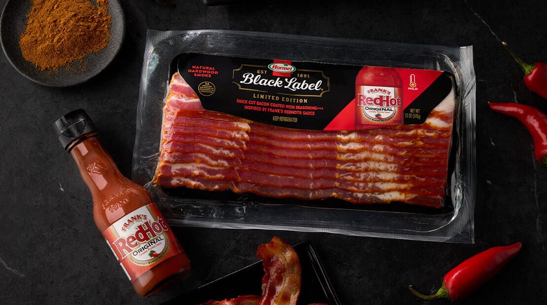A package of Hormel Black Label Frank's RedHot bacon, a bottle of sauce, chili peppers, and seasoning.