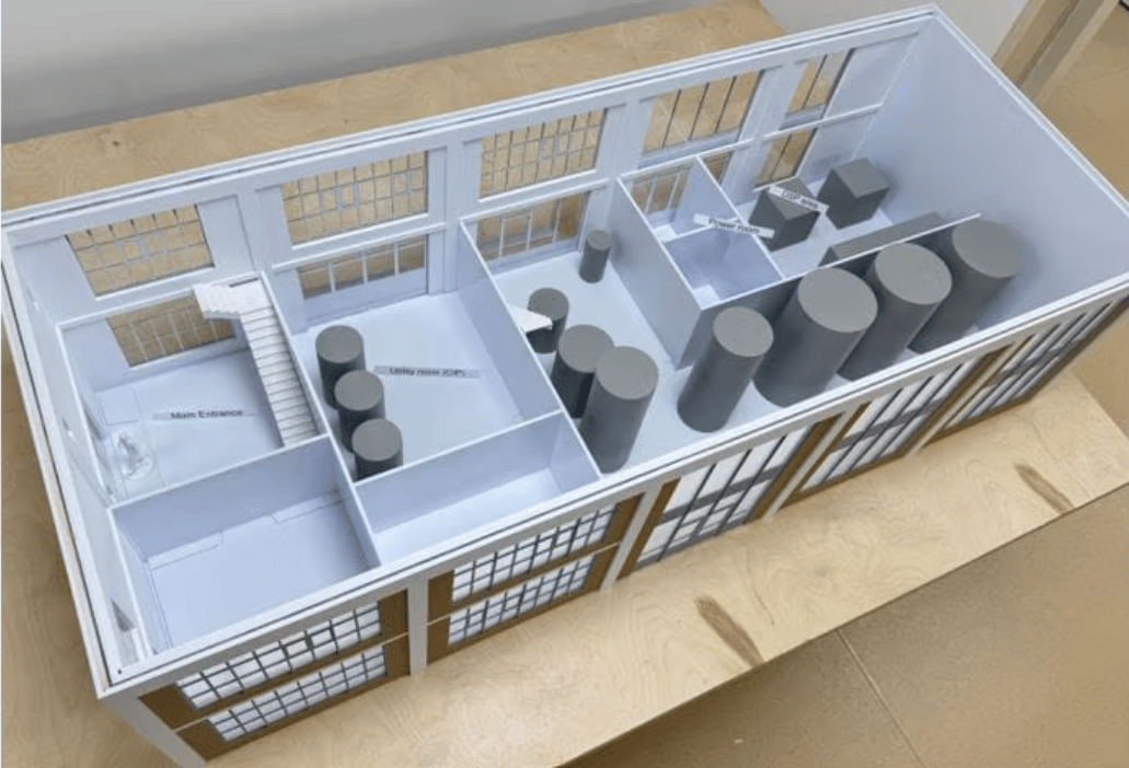 Overhead view of a detailed architectural model showing an industrial building's interior layout with various rooms and equipment.
