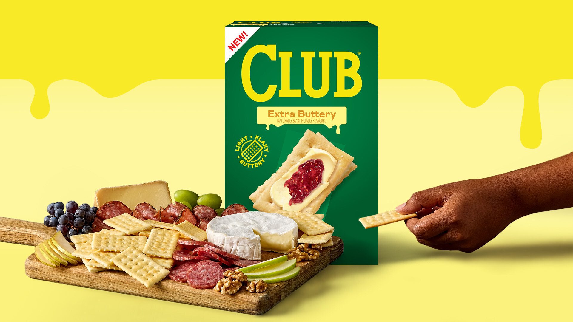 Club Extra Buttery Crackers box next to a charcuterie board with cheese, meats, fruits, and crackers.