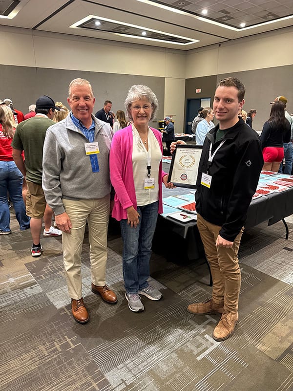 Man, woman, and young man pose with an award certificate at an event.