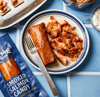 A package of smoked salmon candy next to a plate with a fillet and flaked salmon, and a fork.