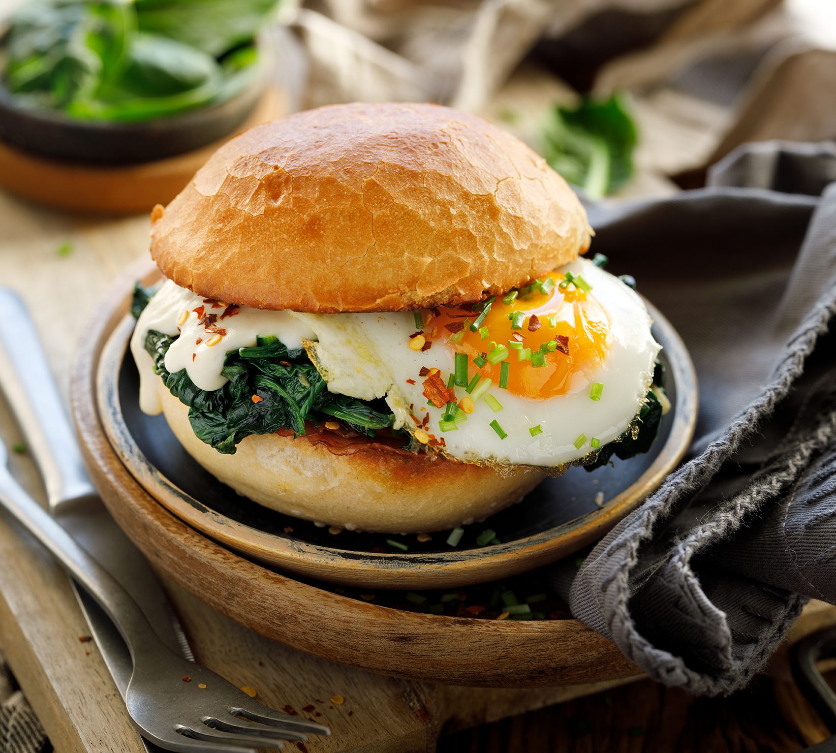 Fried egg and spinach sandwich on a bun.