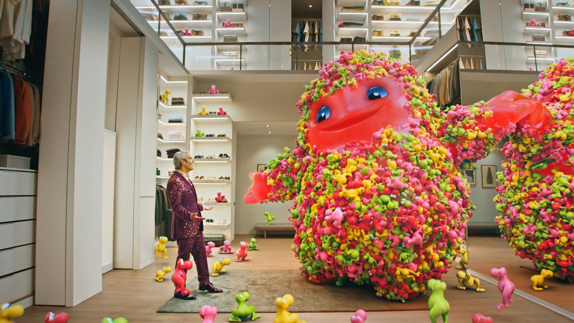 A man in a purple suit stands in a walk-in closet, looking at a large, fuzzy red monster.