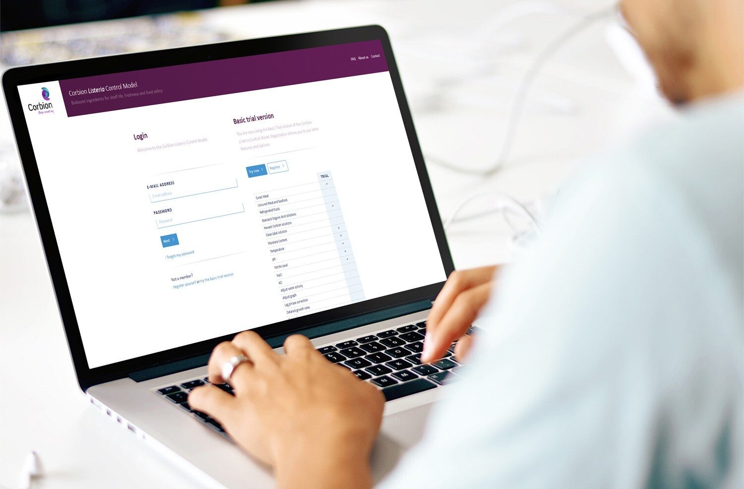 Person typing on laptop displaying Corbion Listeria Control Model website.