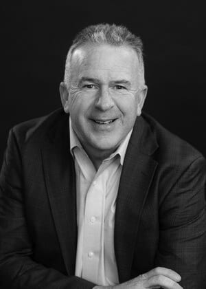 Smiling man in black and white, wearing a suit jacket.