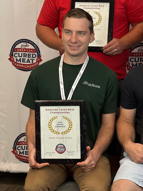 Man holding 2025 Grand Champion Meat Snack Sticks award from American Cured Meat Championships.