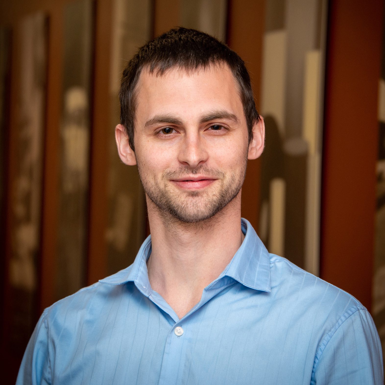 Smiling man in a light blue collared shirt.
