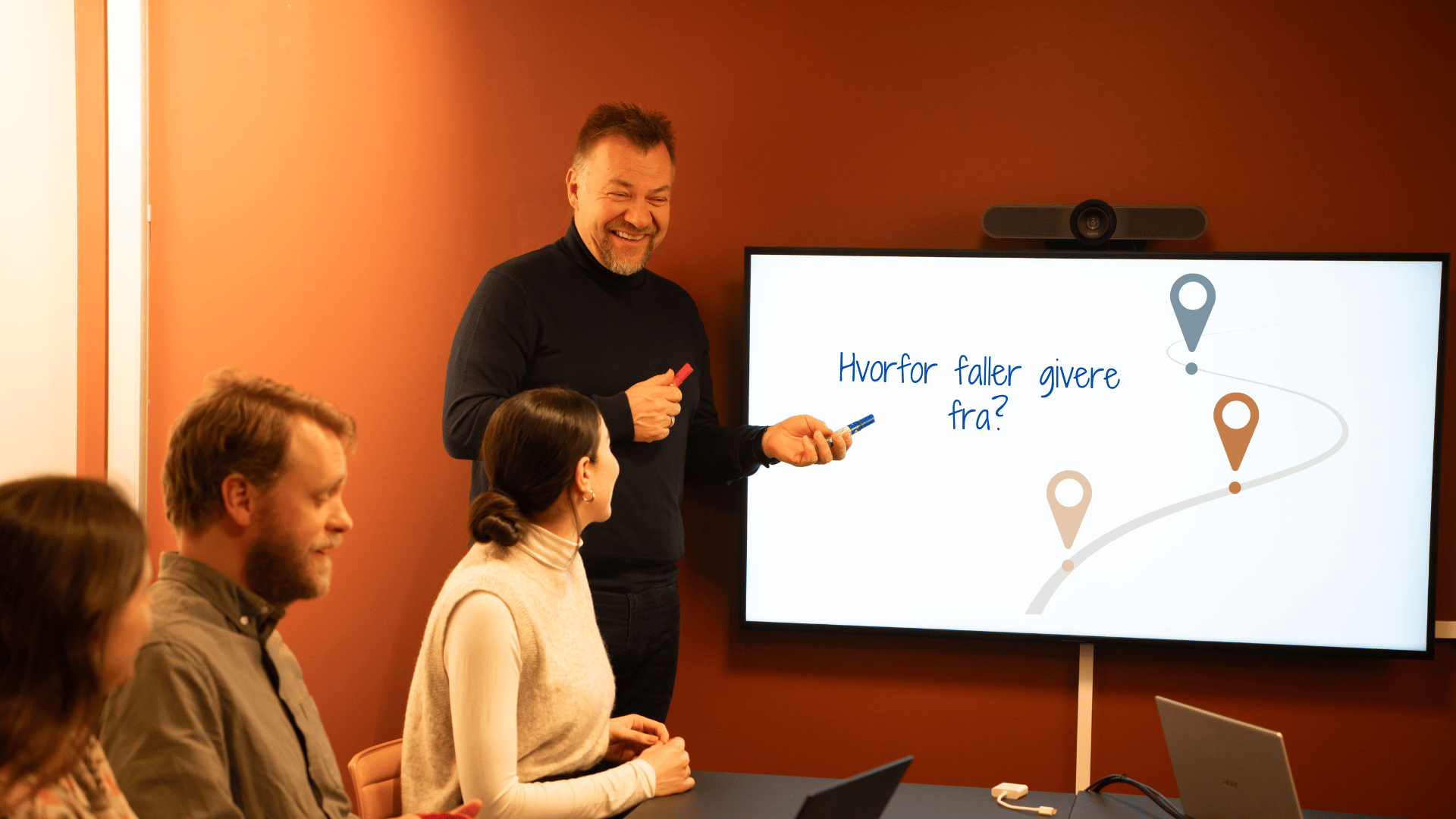 white man with small audience pointing to a whiteboard