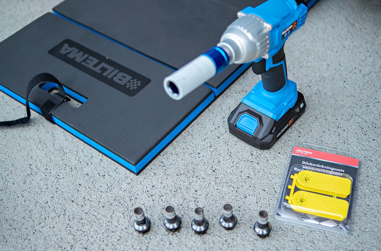 Biltema impact wrench, kneeling mat, tire marking clips, and lug bolts on concrete.