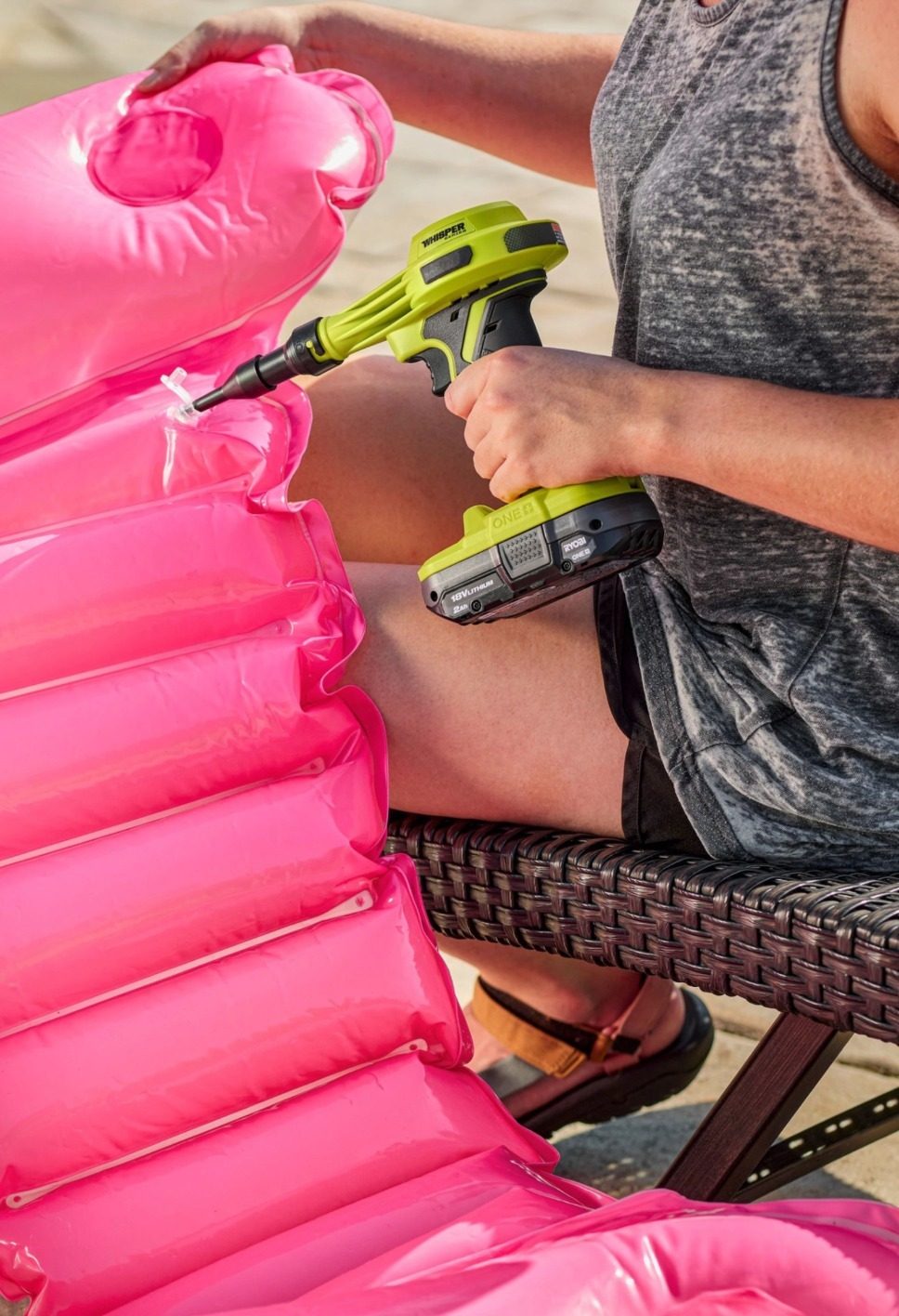 Person using an electric inflator to inflate a pink pool float.