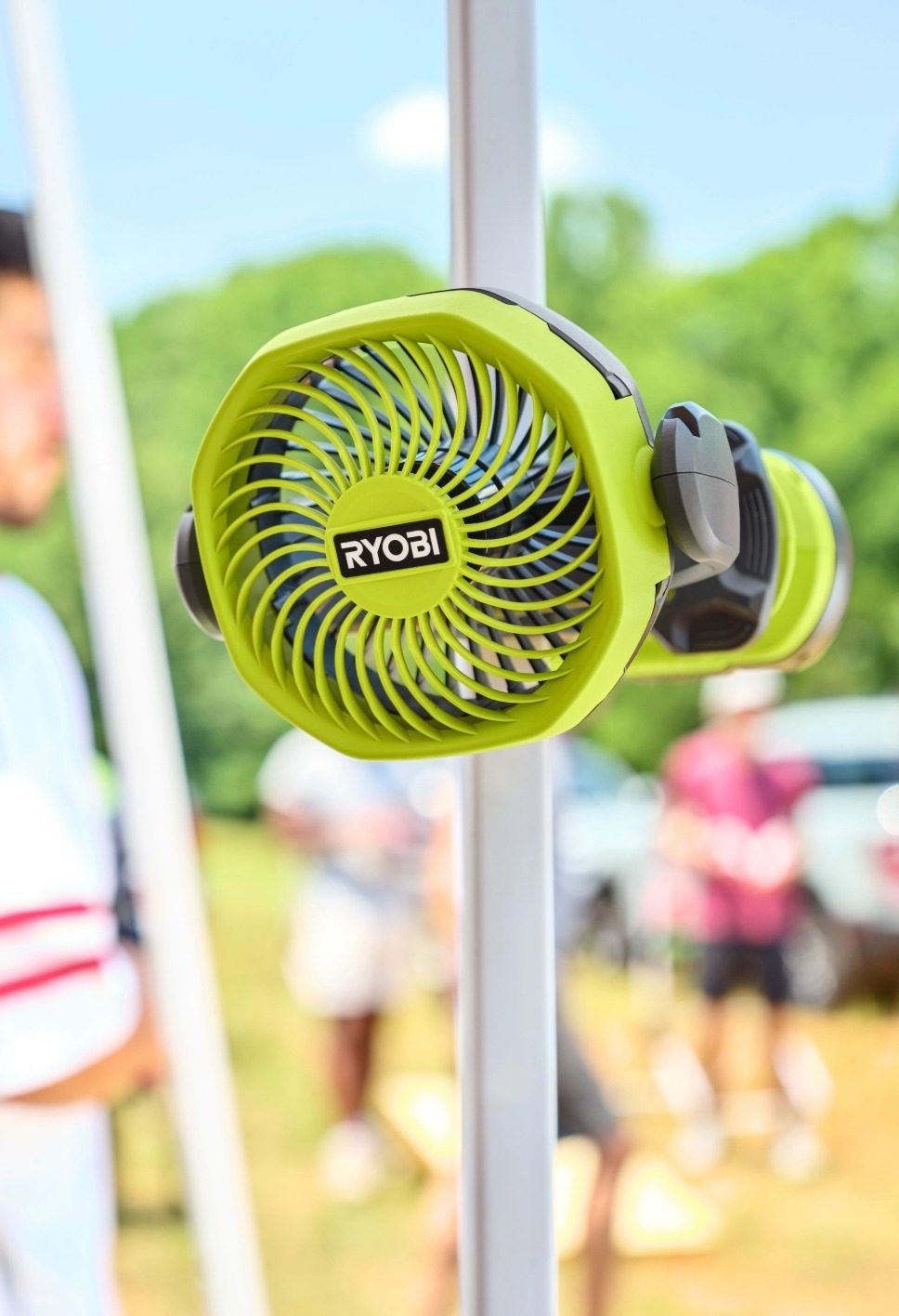 A vibrant lime green Ryobi portable fan with a clip-on design, attached to a white pole outdoors.
