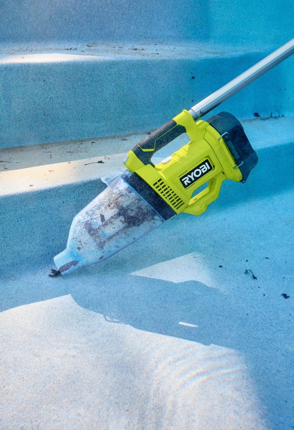 Ryobi pool vacuum cleaning debris from blue pool steps underwater.