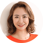 Smiling Asian woman in an orange top, headshot.