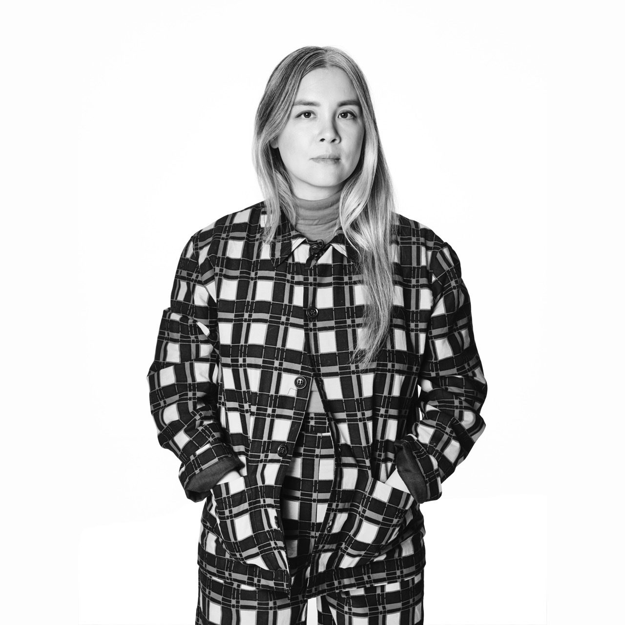 Black and white portrait of a woman with long hair in a plaid outfit.