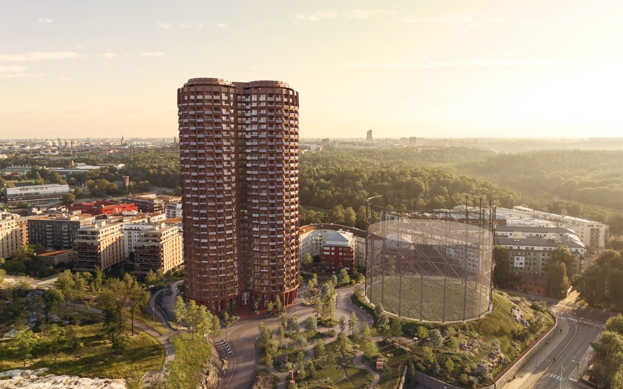 Modern twin towers and a large circular structure in a green city at golden hour.