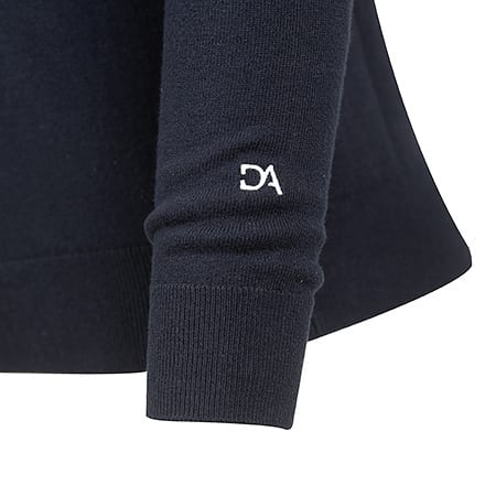 Close-up of a navy blue sweater sleeve with a ribbed cuff and a white "DA" logo embroidered on the arm.