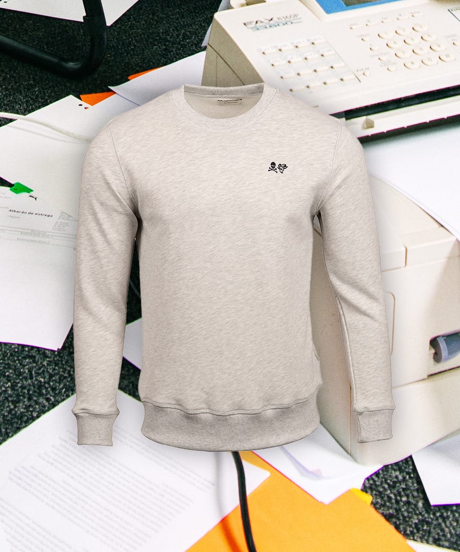 Light gray crewneck sweatshirt with black embroidered skull logo, on a background of office papers.