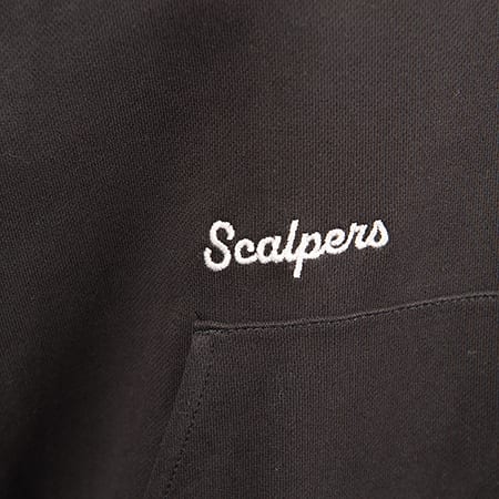 Close-up of white embroidered 'Scalpers' logo on black fabric, likely a hoodie, with a pocket visible.