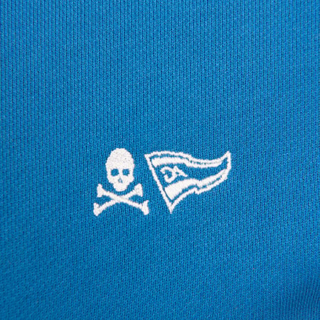 Two embroidered white symbols, a skull and crossbones and a pennant flag with 'DA', on a blue fabric.