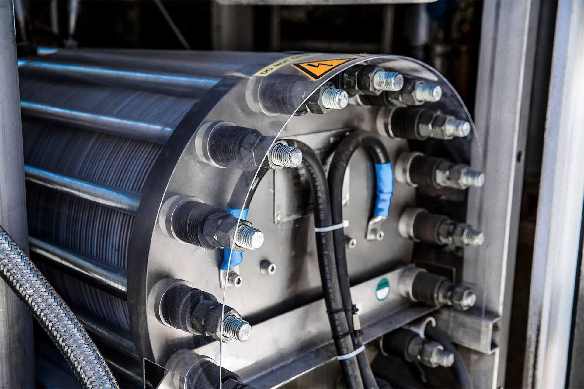 Industrial machinery: cylindrical ribbed component, electrical connections, and a clear safety shield.