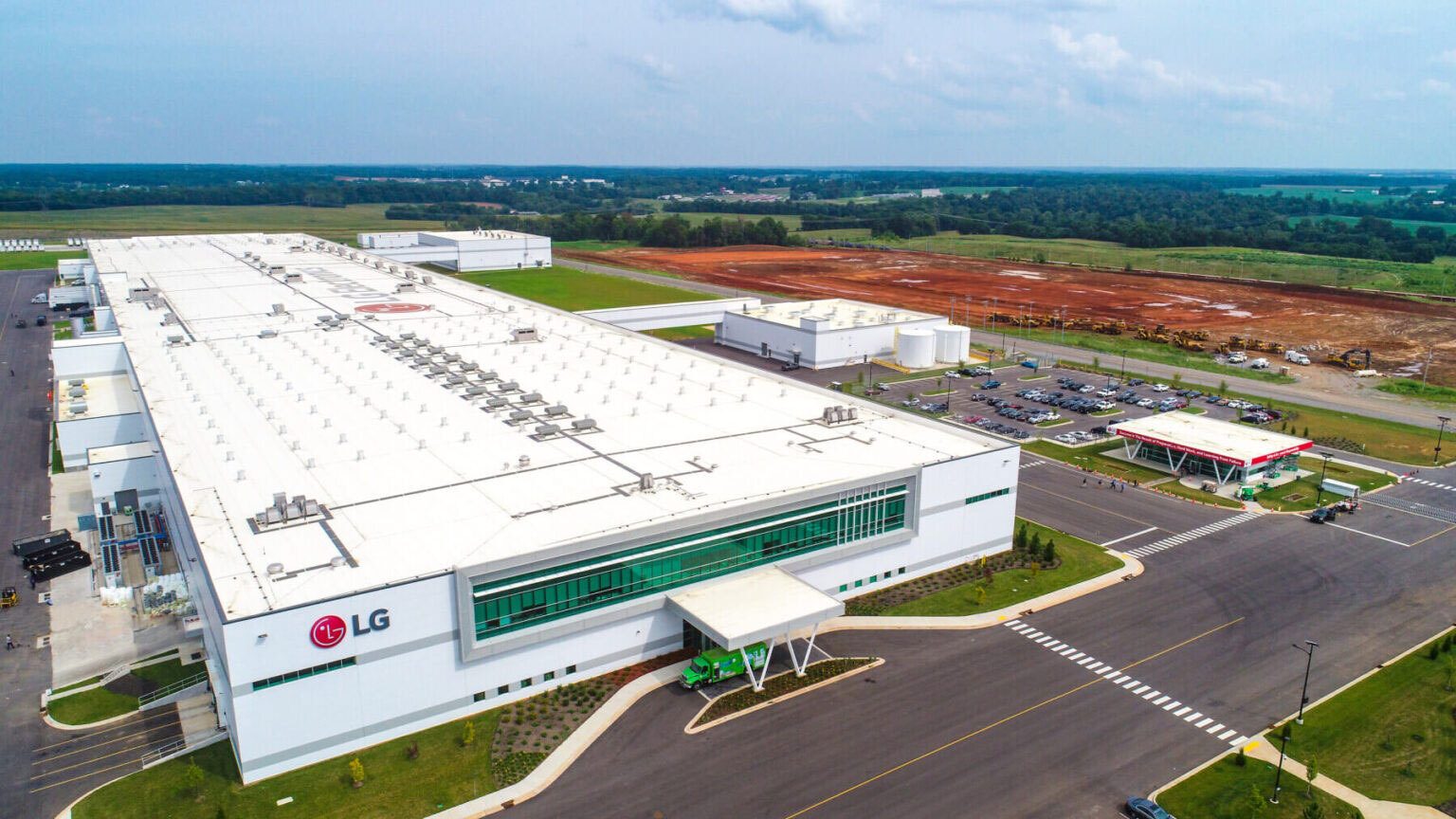 Aerial view of a sprawling LG factory, parking lots, and a red earth construction site.